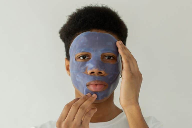 Un jeune homme s'applique un masque de soin bleu sur le visage