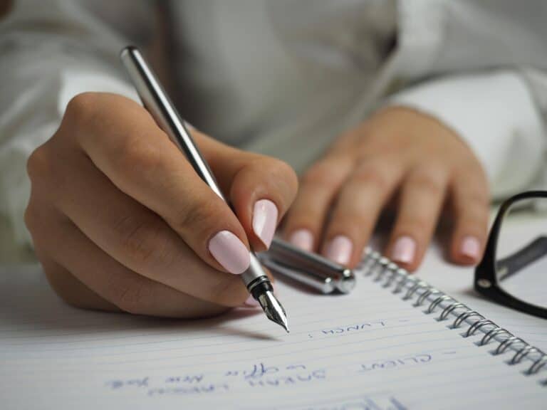 Une femme écrit à la main dans un cahier avec une plume