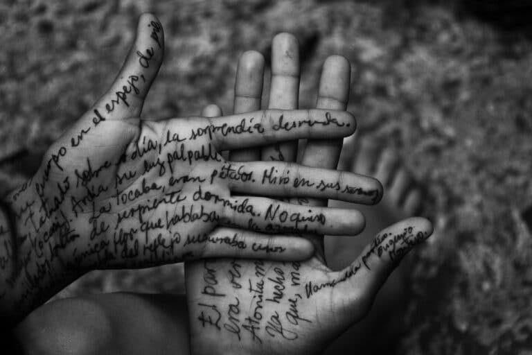 Des mains sont couvertes d'un texte tatoué