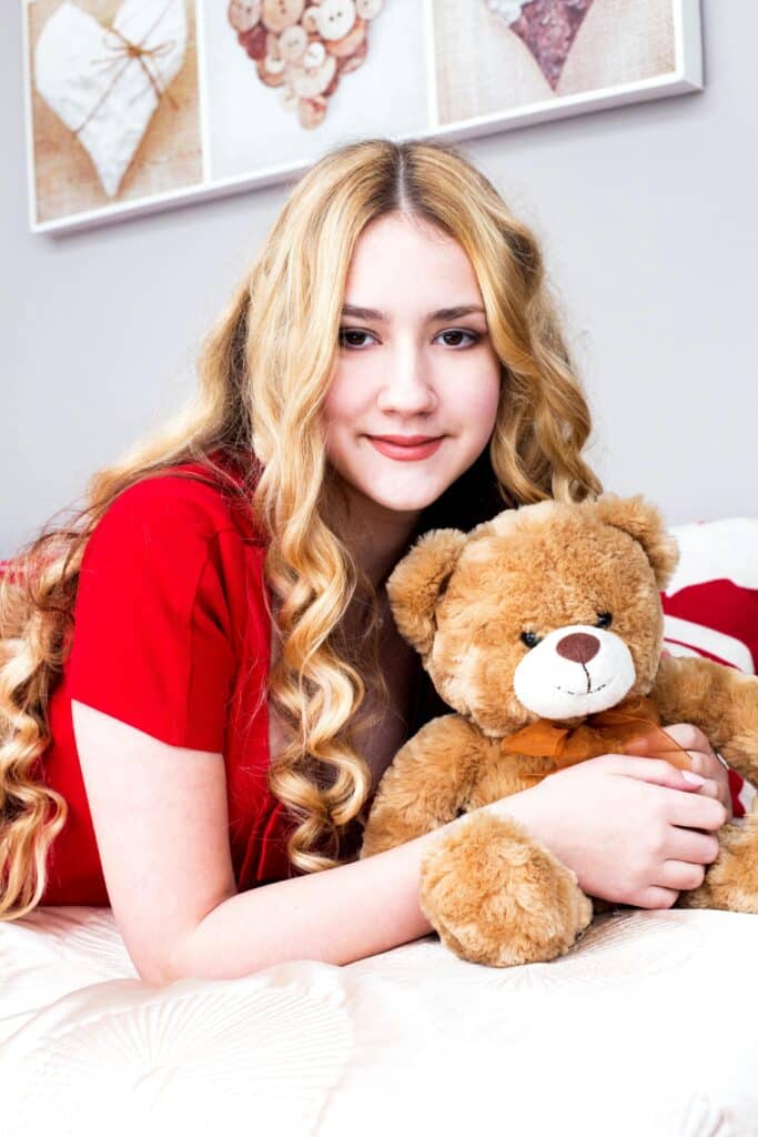 UneAutreVoix-Tiède-Femme - Une Autre Voix Une belle femme aux cheveux blonds avec un ours en peluche dans les bras