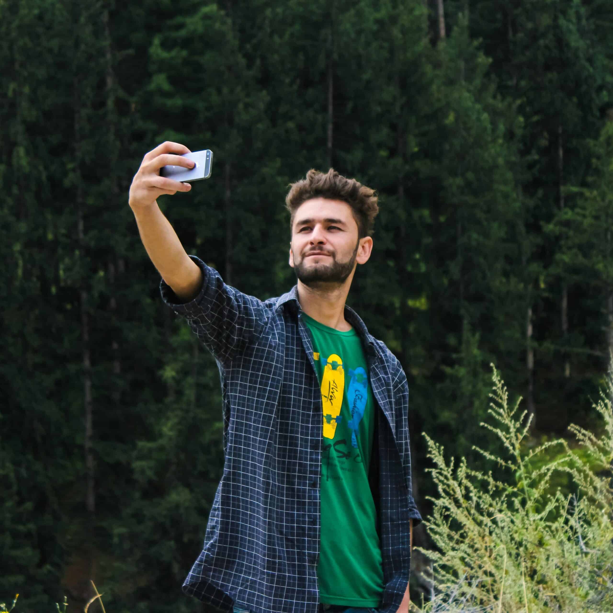 Un homme prend un selfie devant une forêt
