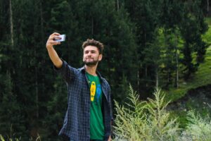 Un homme prend un selfie devant une forêt