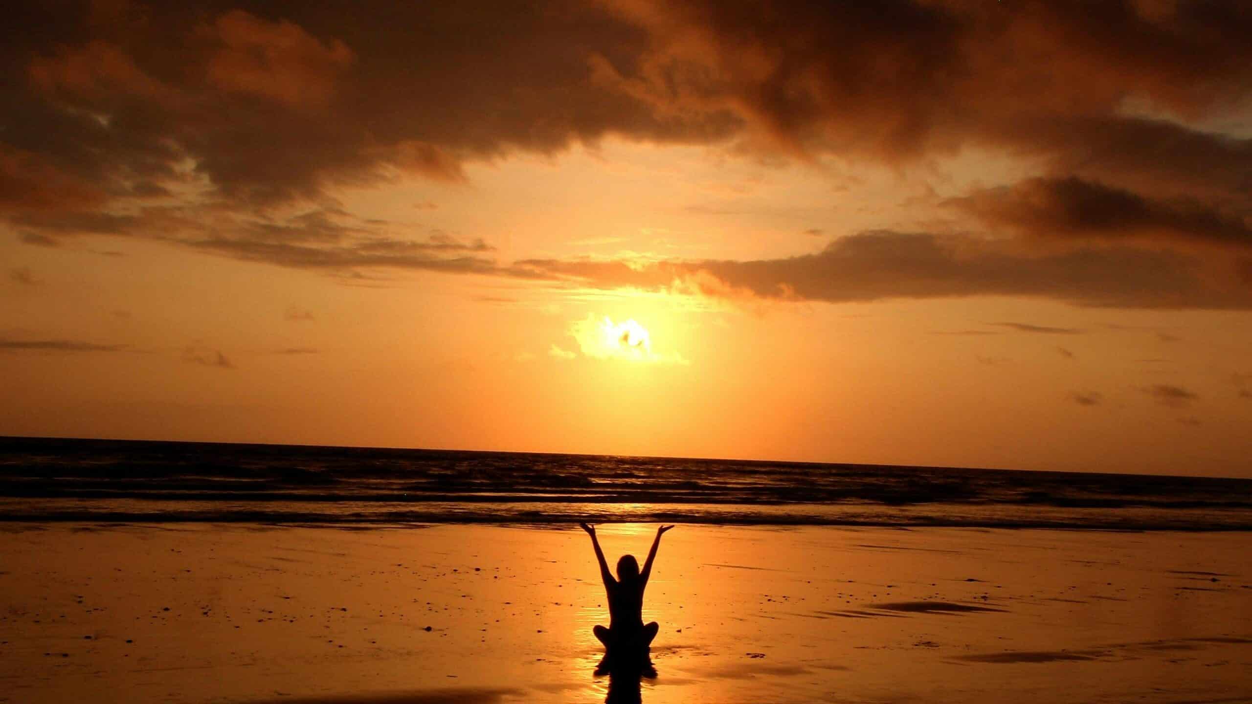 Une femme en lotus au coucher de soleil sur une plage