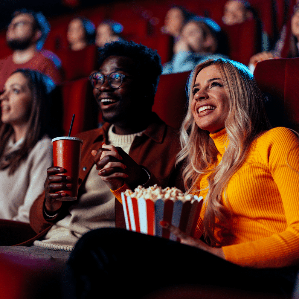 Des personnes rient au cinéma avec du popcorn dans les mains