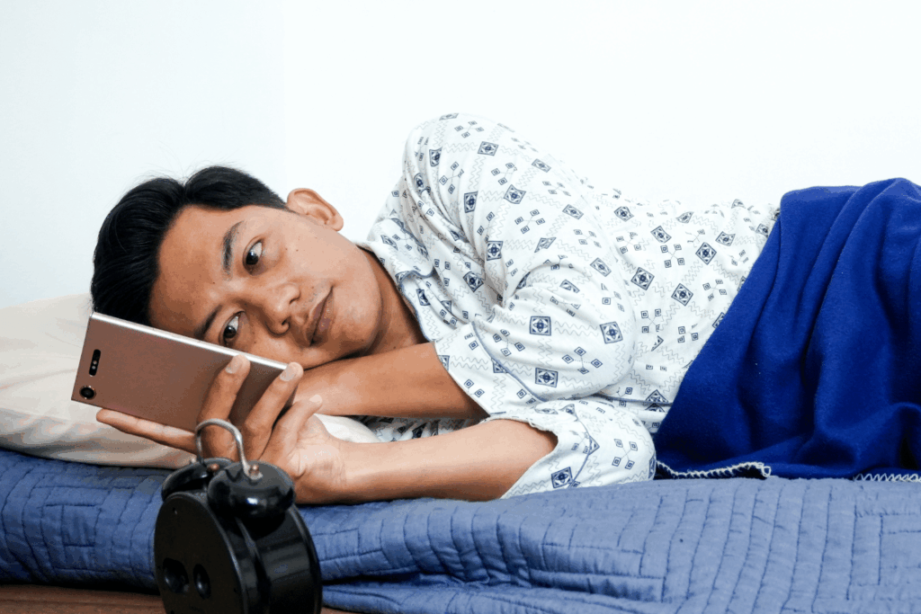 Un homme scrolle sur son téléphone mobile allongé sur le côté