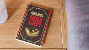 Le livre 1984 de Georges Orwell posé sur un sol en bois