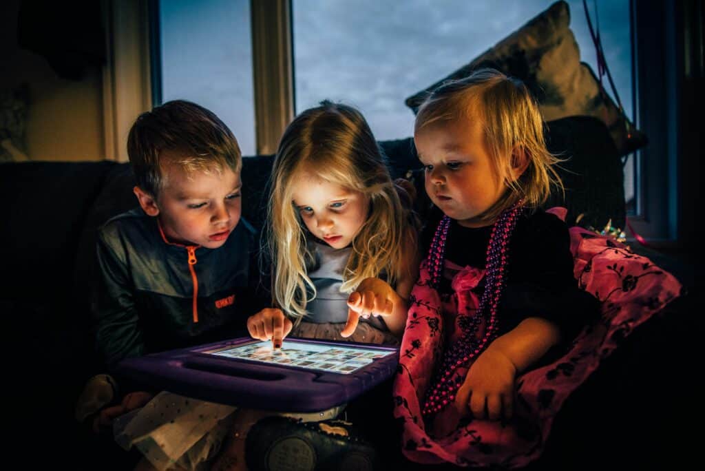 Trois enfants regardent quelque chose sur une tablette rétro-éclairée