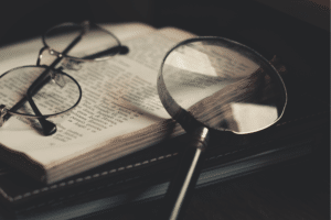 Des lunettes et une loupe d'enquêteur sur un livre ouvert