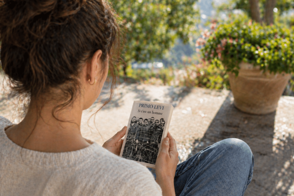 Une femme lit le livre Si c'est un Homme de Primo Lévi sur une terrasse
