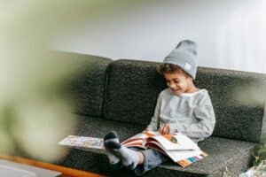 Un enfant lit un livre assis sur un canapé