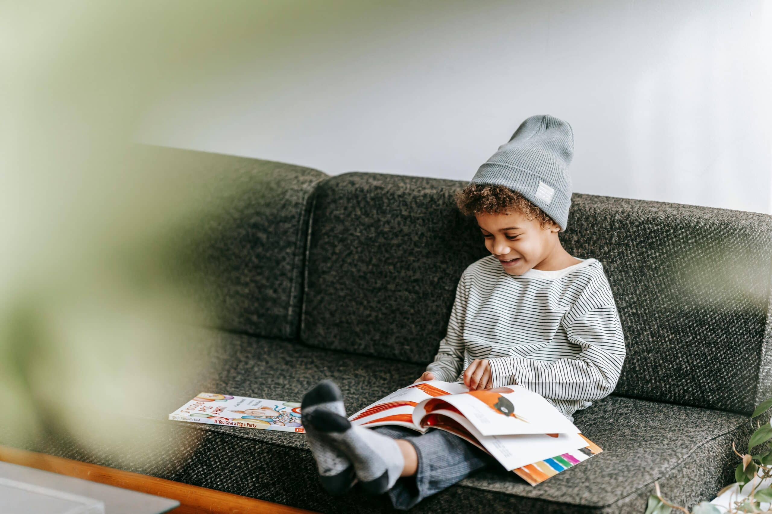Un enfant lit un livre assis sur un canapé