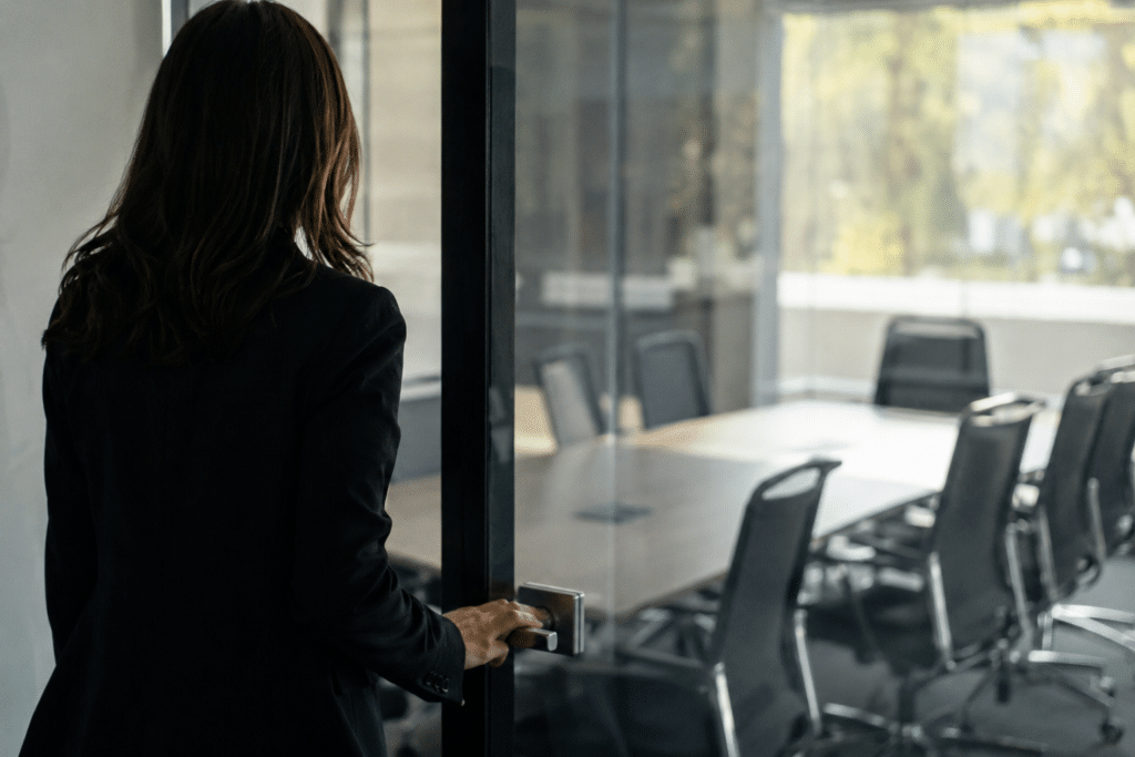 Une femme en costume rentre dans une salle de bureau vide.