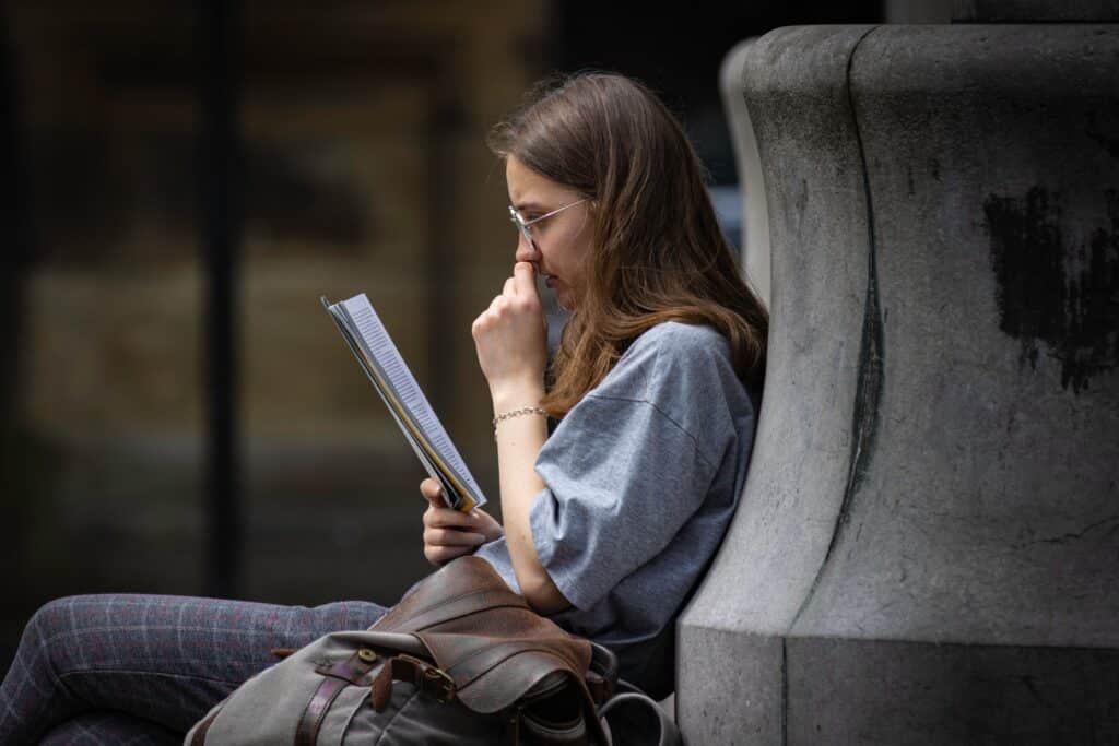 Une femme qui lit un livre dehors et qui semble dérangée.