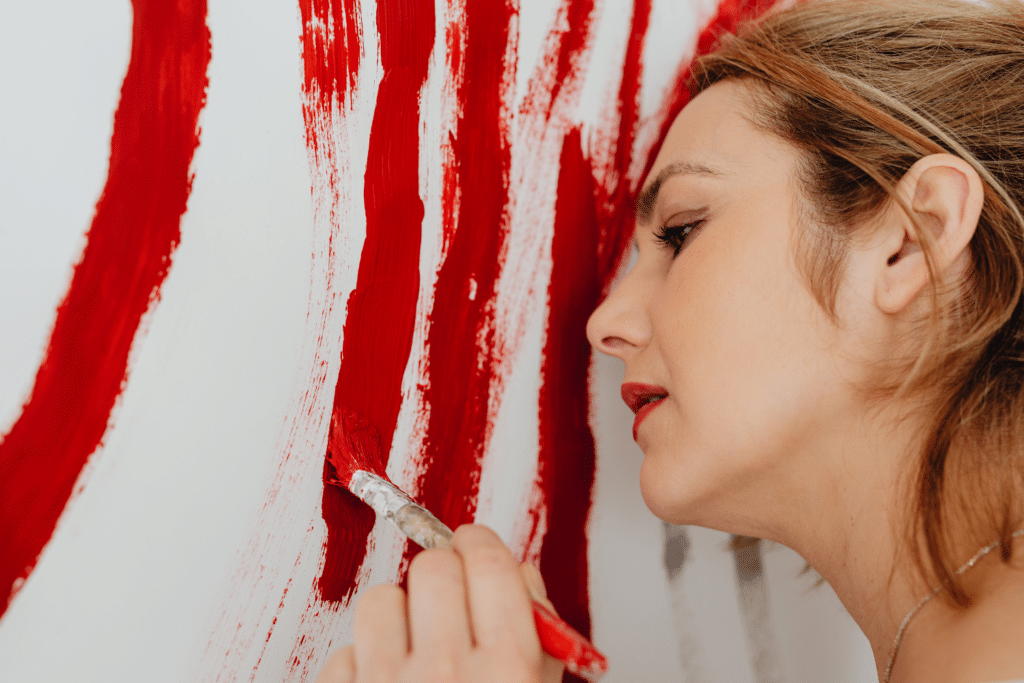 Une femme peint des traits rouges épais sur un mur blanc